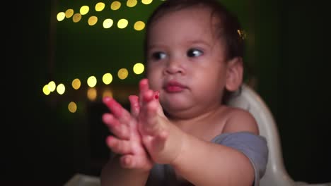 Baby-Junge-Rack-Focus-Pull-Isst-Obst-Mit-Goldenem-Bokeh-Im-Dunklen-Raum-Und-Klatscht-Fröhlich-In-Die-Hände
