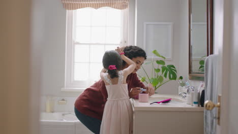 happy little girl brushing mothers hair in bathroom mom getting daughter ready in morning enjoying parenthood caring for child