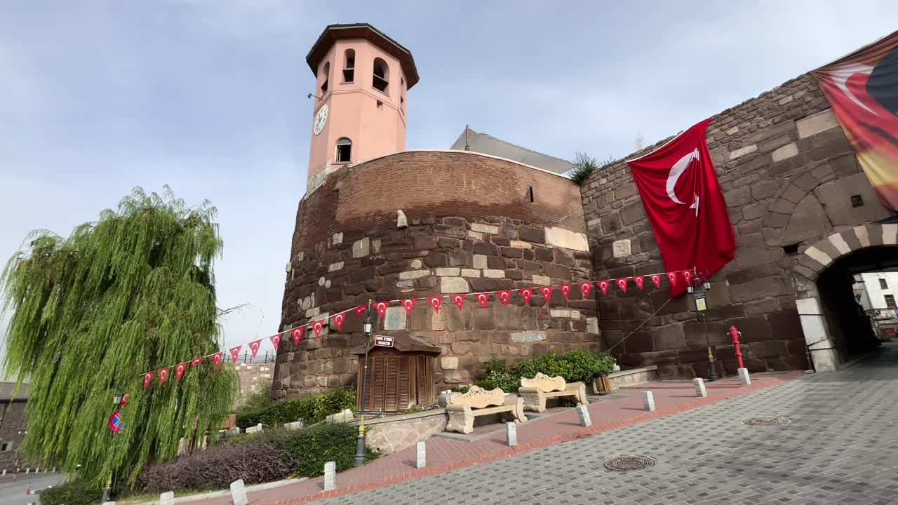 Turkey,Ankara,Ankara Castle decorated with small Turkish flags,one huge Turkish Flag on the left and a flag with Ataturk's photo on the right side of the entrance, white clouds with blue skies.