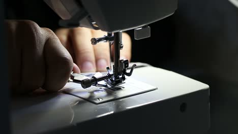 con pequeñas tijeras de metal preparando hilo de coser en máquina de coser