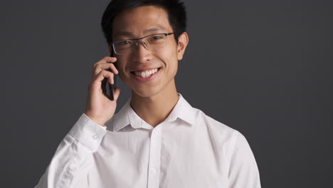 hombre asiático felizmente hablando en el teléfono inteligente.