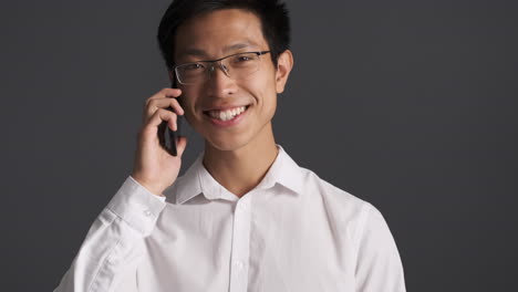 asian man happily talking on smartphone.