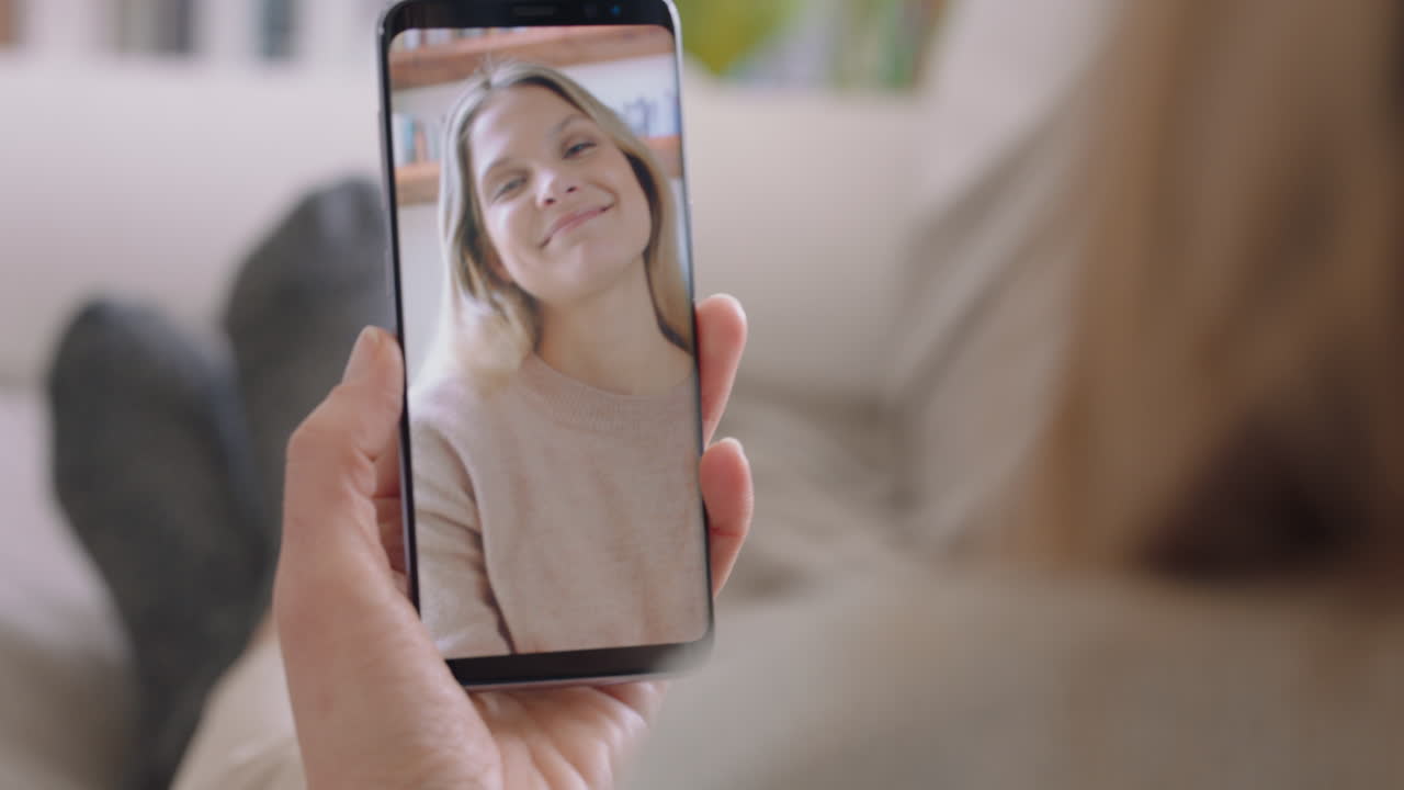 mujer joven teniendo video chat usando teléfono inteligente en casa hablando con un amigo disfrutando de la conversación compartiendo estilo de vida en el teléfono móvil orientación vertical 4k metraje