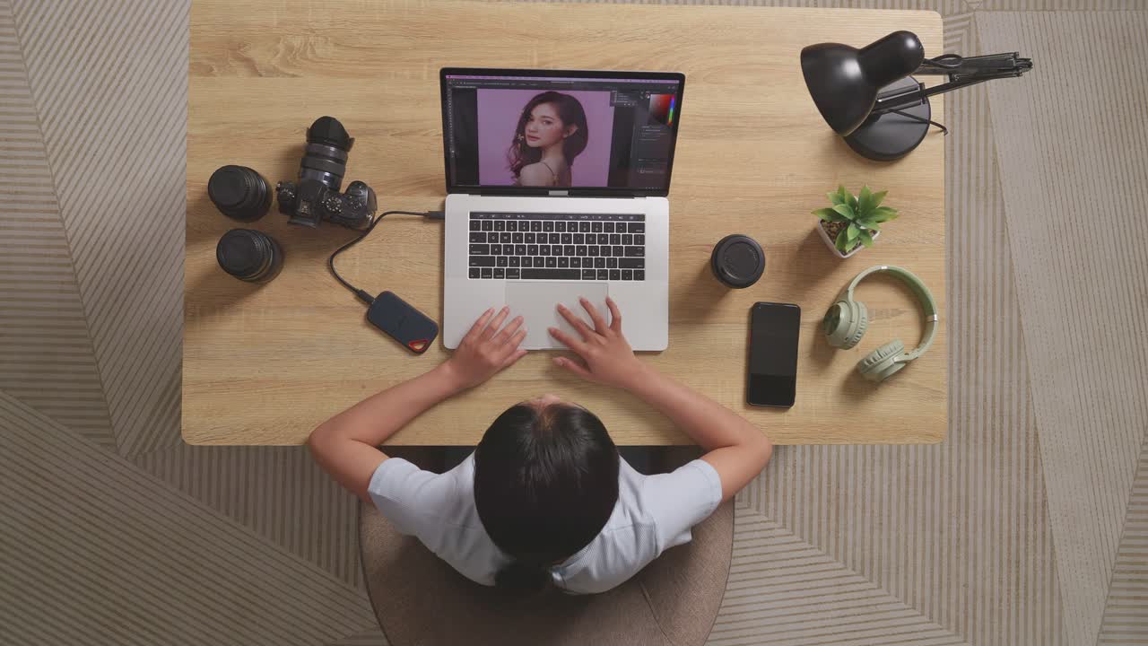 Top View Of A Woman Editor Sitting In The Workspace Using A Laptop Next To The Camera Editing Photo Of A Woman At Home