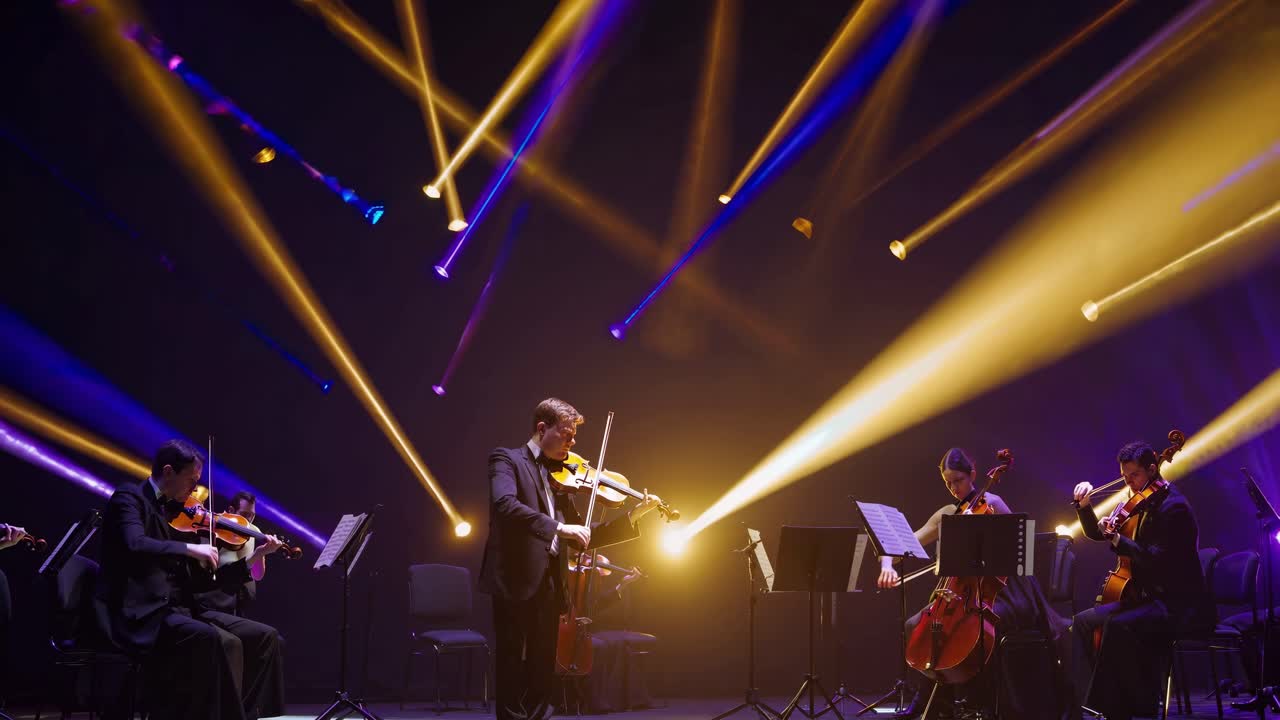 Professional musicians skillfully playing violins and cellos on a stage, bathed in vibrant spotlights, create a captivating atmosphere during a mesmerizing orchestral performance