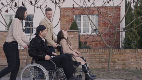 side view of woman and man taking a walk with her disable friends in wheelchair around the city