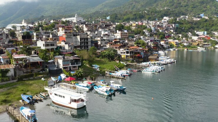 Il drone si avvicina lungo la riva del Lago Atitlán, Guatemala, mostrando barche turistiche e yacht al margine della città vecchia.