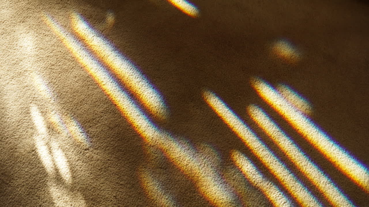 Sunlight refracted through cut glass moves across a carpeted floor in time-lapsed motion