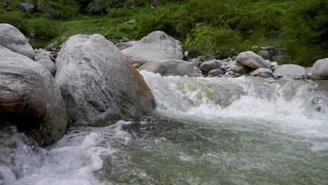 Agua-Fresca-De-Arroyo-Que-Fluye-Sobre-Grandes-Rocas,-Rodeada-De-Exuberante-Vegetación-Y-Belleza-Natural-En-Un-Entorno-Tranquilo.