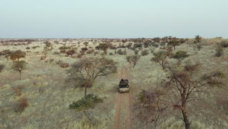 safari truck driving in african landscape in the namibia grasslands, aerial