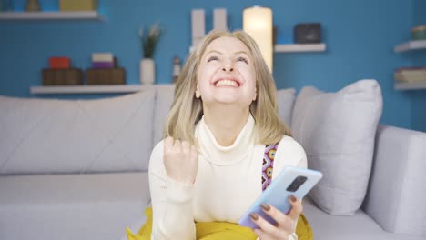 una joven rubia mirando el teléfono y regocijándose.