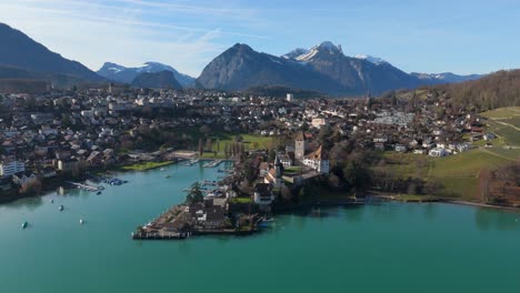 spiez am thunsee mit yachthafen und alpen im hintergrund, klarer himmel, luftansicht