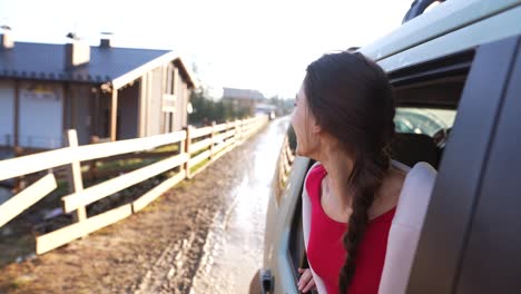 mujer riendo mientras mira por la ventana de un coche en un campo pintoresco