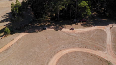 Aerial-view-following-ATVs-on-a-quad-bike-track,-sunny-day-in-Australia---pan,-drone-shot