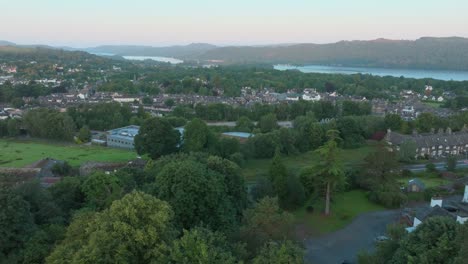 treetops with camera rise showing rural urban setting with lake. summer. windermere, cumbria, uk