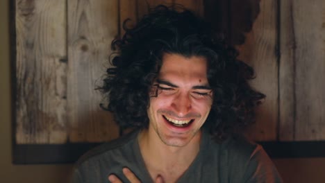 joyful man laughing and wiping tears while watching viral video on laptop