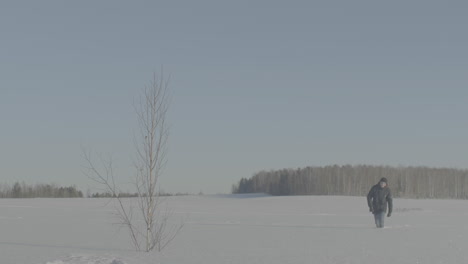 man walking in a snowy field on a cold winter day