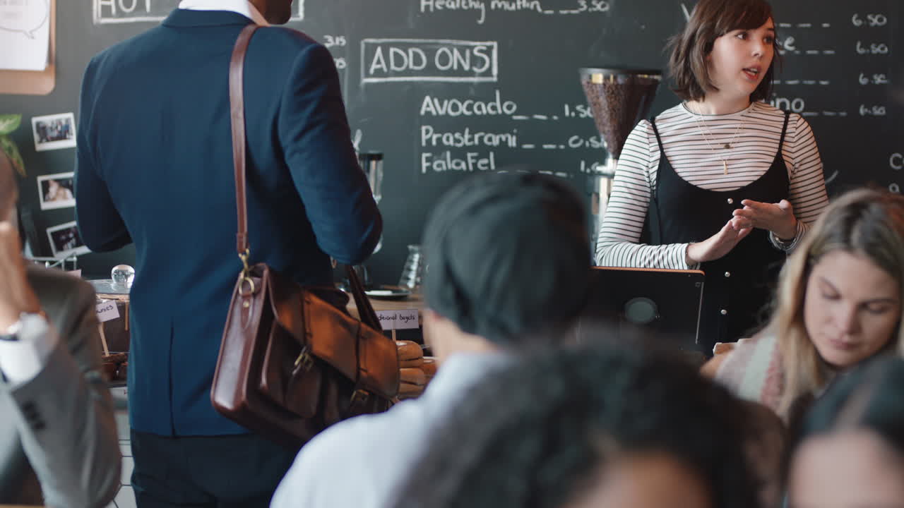 카페 바리스타에서 다양한 사람들이 바쁜 레스토랑에서 커피를 구입하는 고객을 섬기는 여성