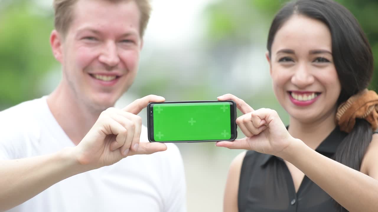 젊은 다민족 커플이 거리에서 함께 전화를 하고 있습니다.