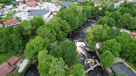closing in on morrum river in morrum town, sweden, with greenery and buildings, aerial