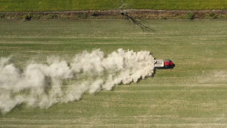 Tractor-Agrícola-Esparciendo-Polvo-Blanco-Por-Encima-De-La-Sobrecarga-De-Vista-Amplia