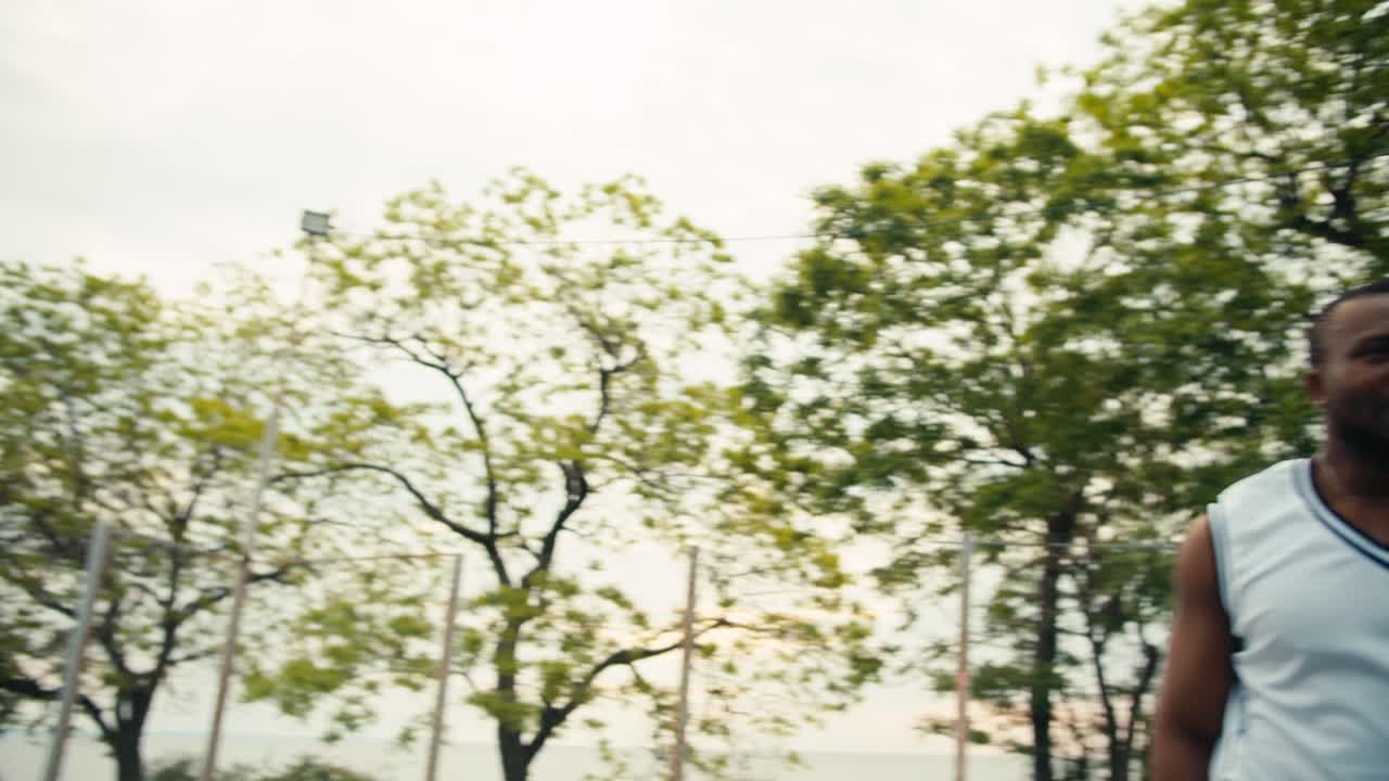 una persona negra con una camiseta blanca lanza efectivamente una pelota de baloncesto en el aro en la cancha de baloncesto. video filmado en alta definición