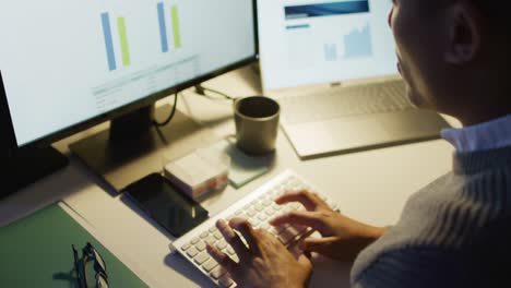 Video-of-tired-biracial-man-using-computer,-working-late-in-office