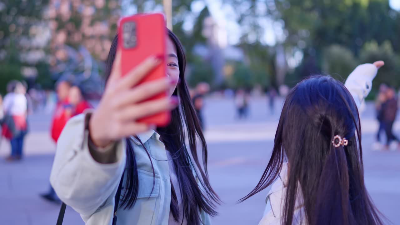 Due giovani donne felici che fanno una videochiamata selfie all'aperto