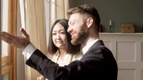 bearded man talking to an woman while standing near the window in the morning