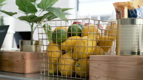 Metal-basket-filled-with-yellow-lemon-lemonade-limon-citrus-sour-limes-lime-evergreen-trees-strong-plant-flavor-countertop-close-up-colorful-fruity-fruits-banana-bananas-café-fresh-healthy-diet