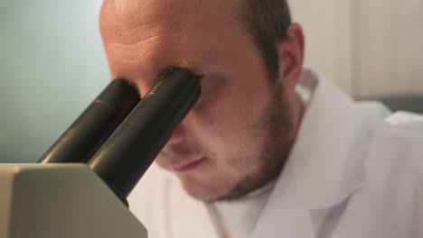 una vista de cerca de un técnico fijó sus ojos en un microscopio en un laboratorio, el primer plano muestra las lentes del microscopio