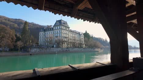 viendo un hermoso edificio junto al río desde una hendidura en un puente cubierto, thun