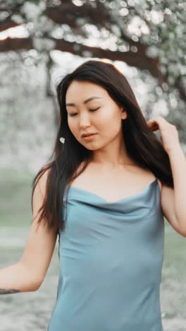 asian woman in a blue silk dress in a spring garden