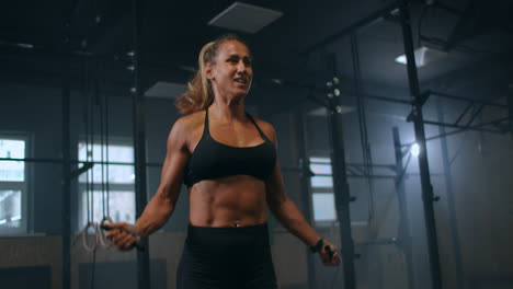 strong muscular young woman rope skipping as warm up. fitness concept. young slim woman jumping with skipping rope in gym. close-up of female feet jumping in mid air whilst using skipping rope.