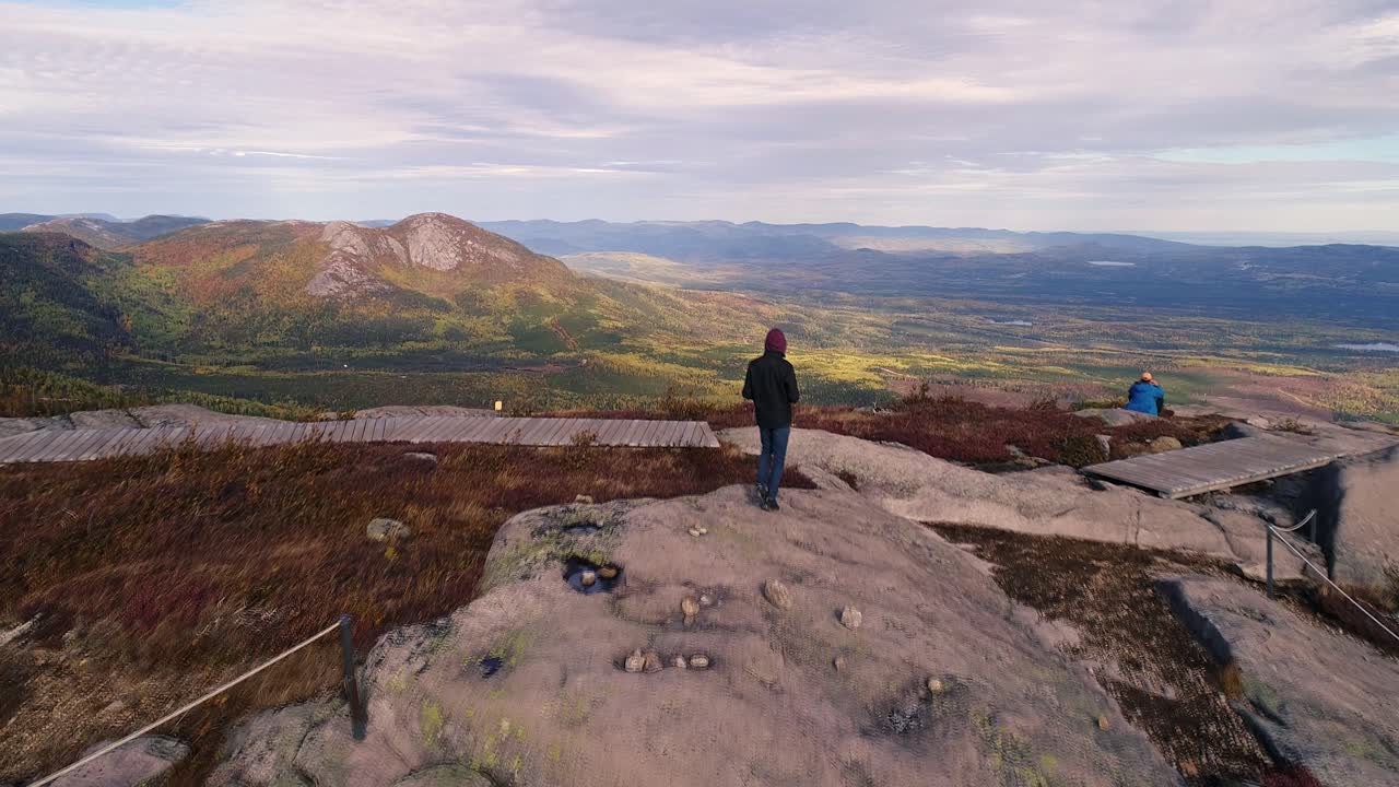 한 청년이 큰 바위 위를 걷고 아름다운 경치를 즐긴다