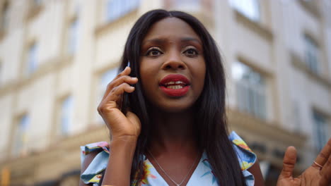 afro girl having phone conversation on street. lady talking smartphone in city