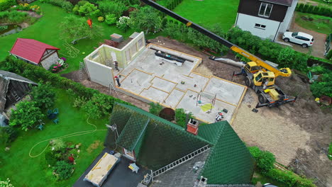 industrial crane constructing private home, aerial fly away view