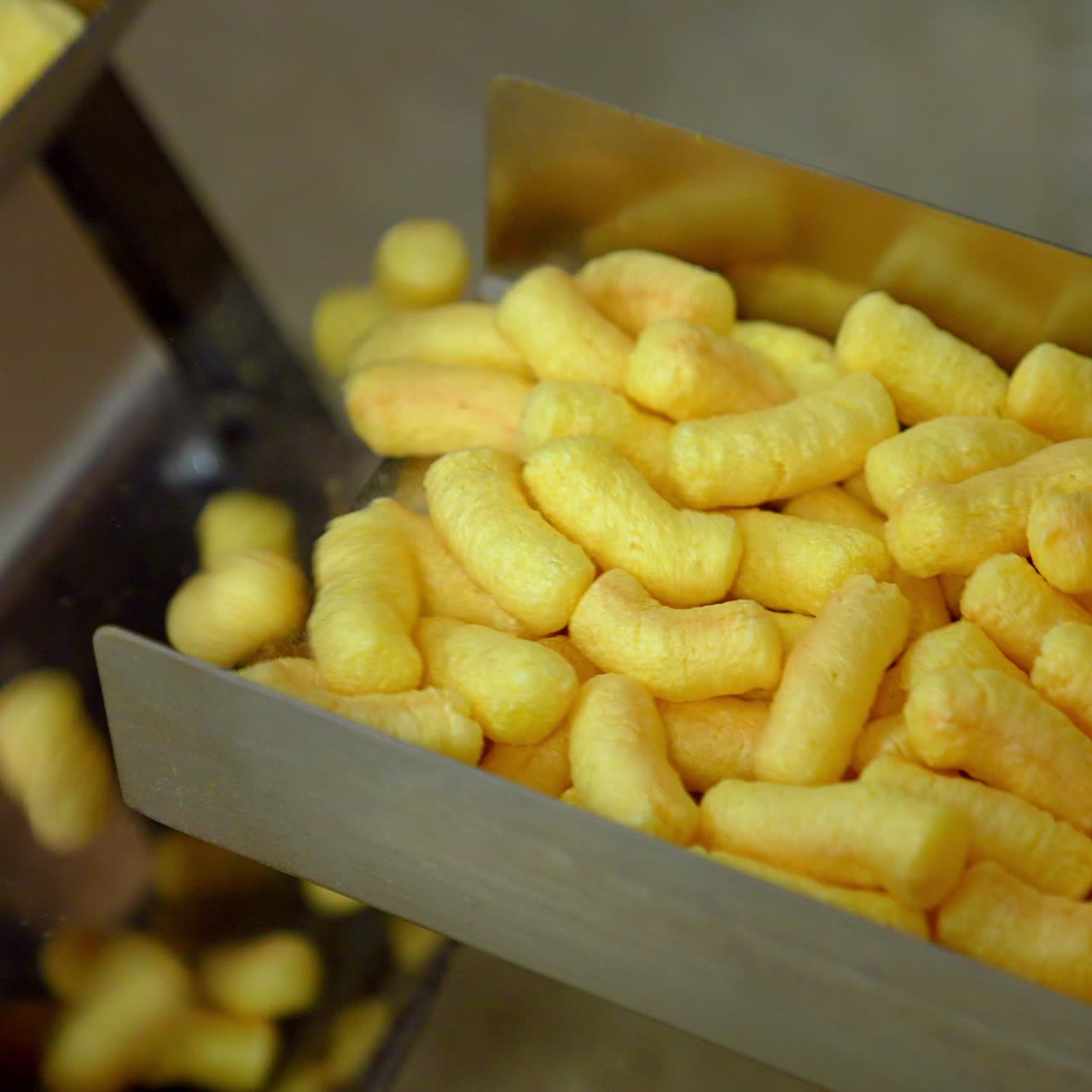 Puffcorn making close up. Sweet golden corn sticks factory