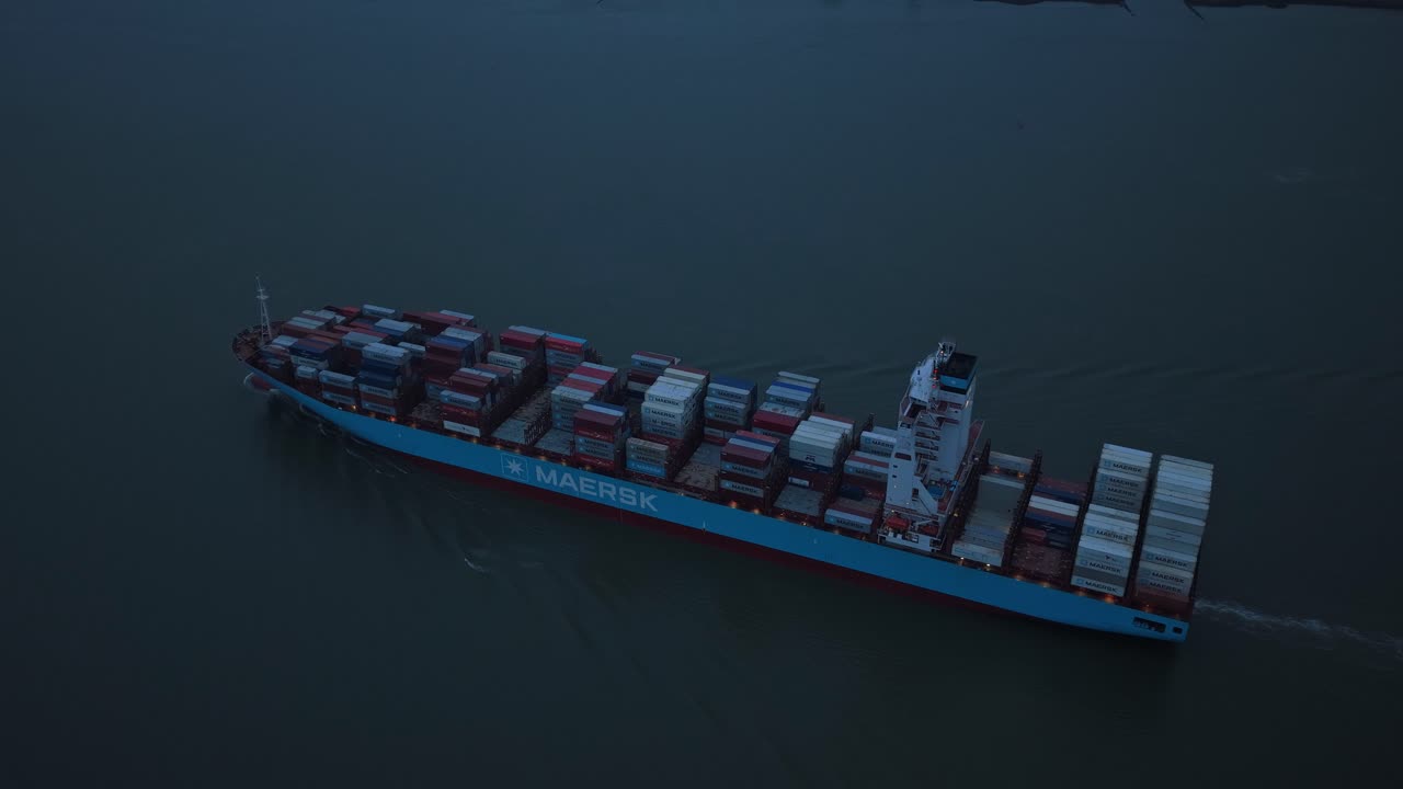 Container ship sailing through Elbe River during blue hour aerial shot