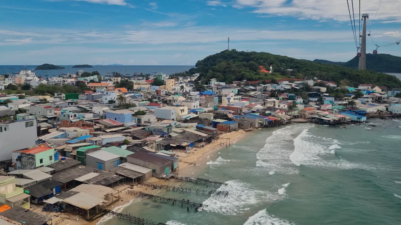 From the world’s longest cable car on Phu Quoc, aerial view of An Thoi’s coastline with waves lapping the shore and Hòn Thơm rising on the horizon under autumn clouds, Vietnam