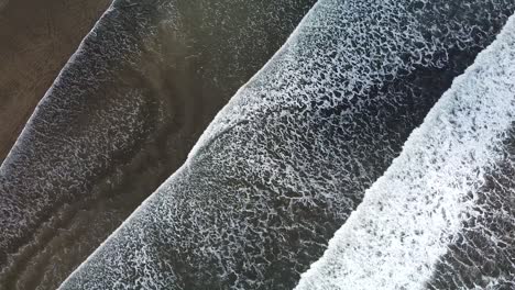 beautiful drone shot flying over the black sand beach in costa rica