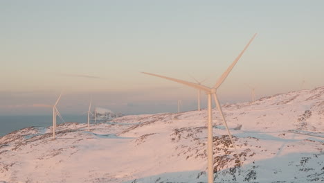 Winter-Sunrise-Scenery-Of-Wind-Turbines-Spinning-On-Snow-covered-Wind-Farm-In-Norway