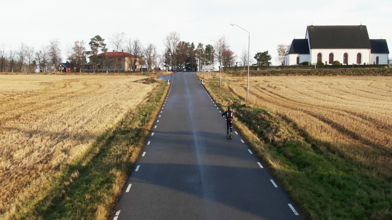 스키를 타고 스웨덴의 시골 도로를 오스테르순 근처로 가는 남성, 해가 지는 동안