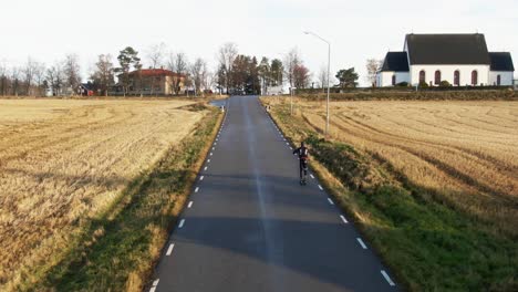 man skiing up swedish countryside rural road near ostersund, sweden during sunset