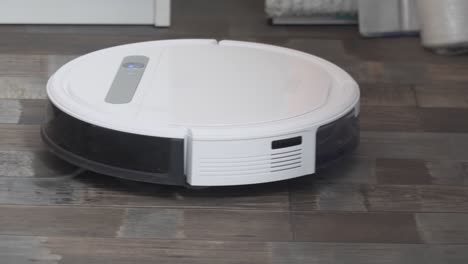 hogar inteligente. la aspiradora robot realiza la limpieza automática del apartamento en un determinado momento. ayudante inteligente en el hogar. un moderno limpiador robótico limpia el polvo en el suelo. tecnología de limpieza