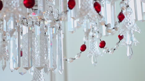 close up of vintage chandlier with shiny white and red gem beads, refracting sun light with colorful flares in living room