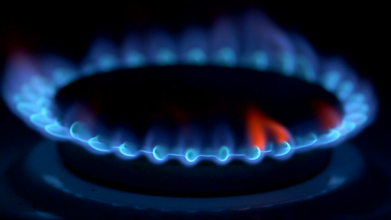 Gas stove firing up with blue flame in the darkness. UHD