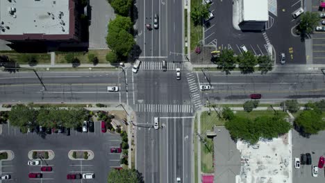 vehicles crossing and driving through intersection in urban city streets, aerial