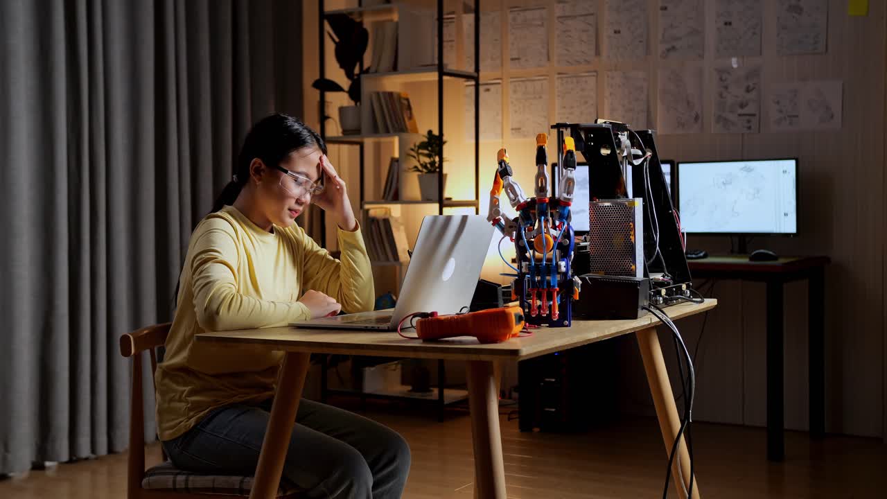 집에서 노트북을 사용하는 사이보그 손에 대해 일하는 동안 두통을 고 있는 아시안 십대 소녀