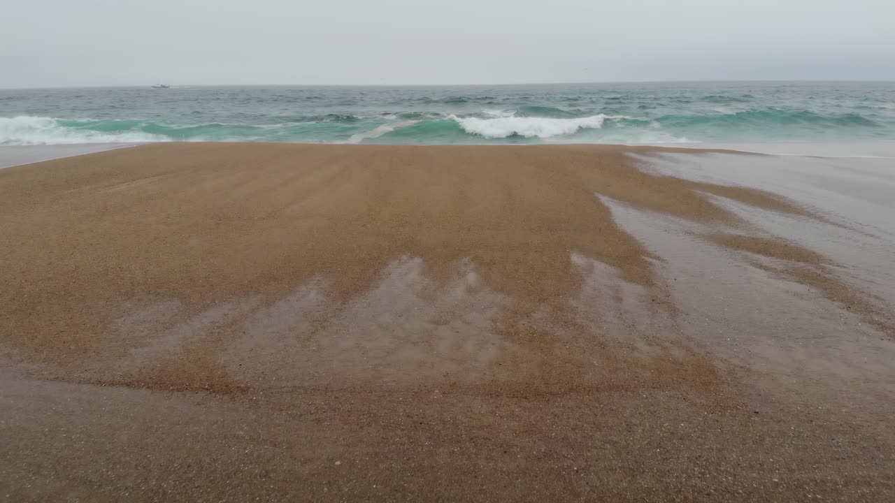 Drone view of waves hitting the shore on the beach in Portugal